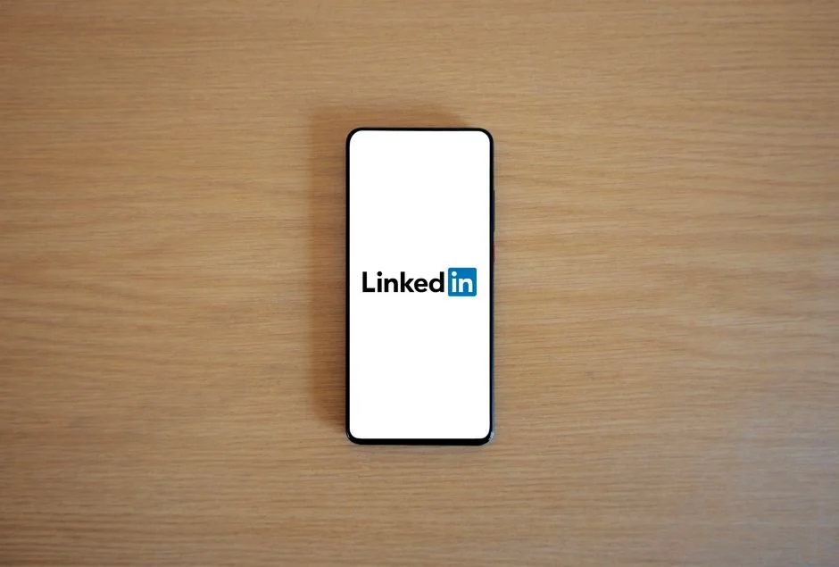 Une personne consulte des données boursières sur un smartphone et un ordinateur portable, en intérieur.