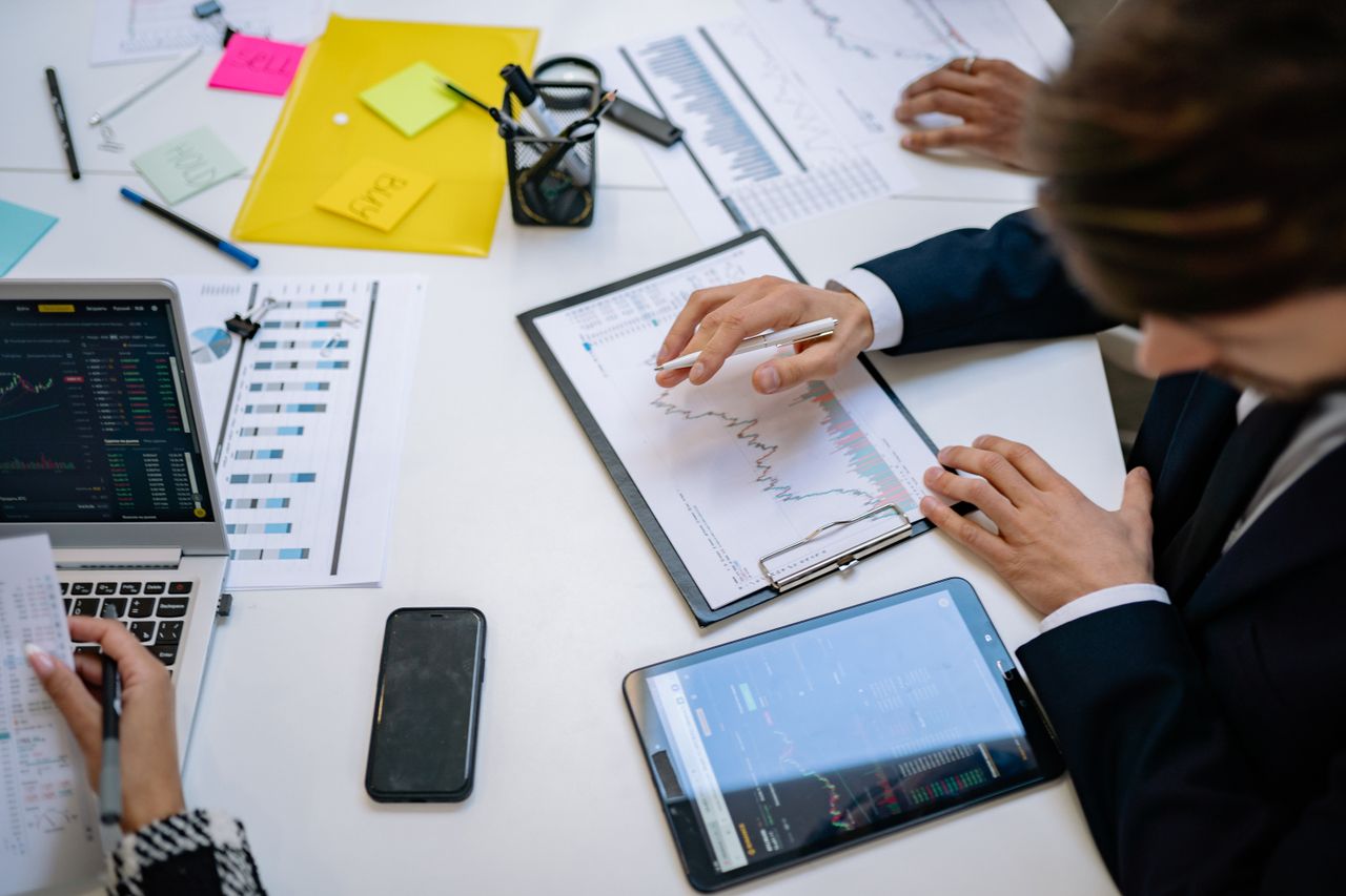 A team examining financial charts and digital data on tablets in an office environment.