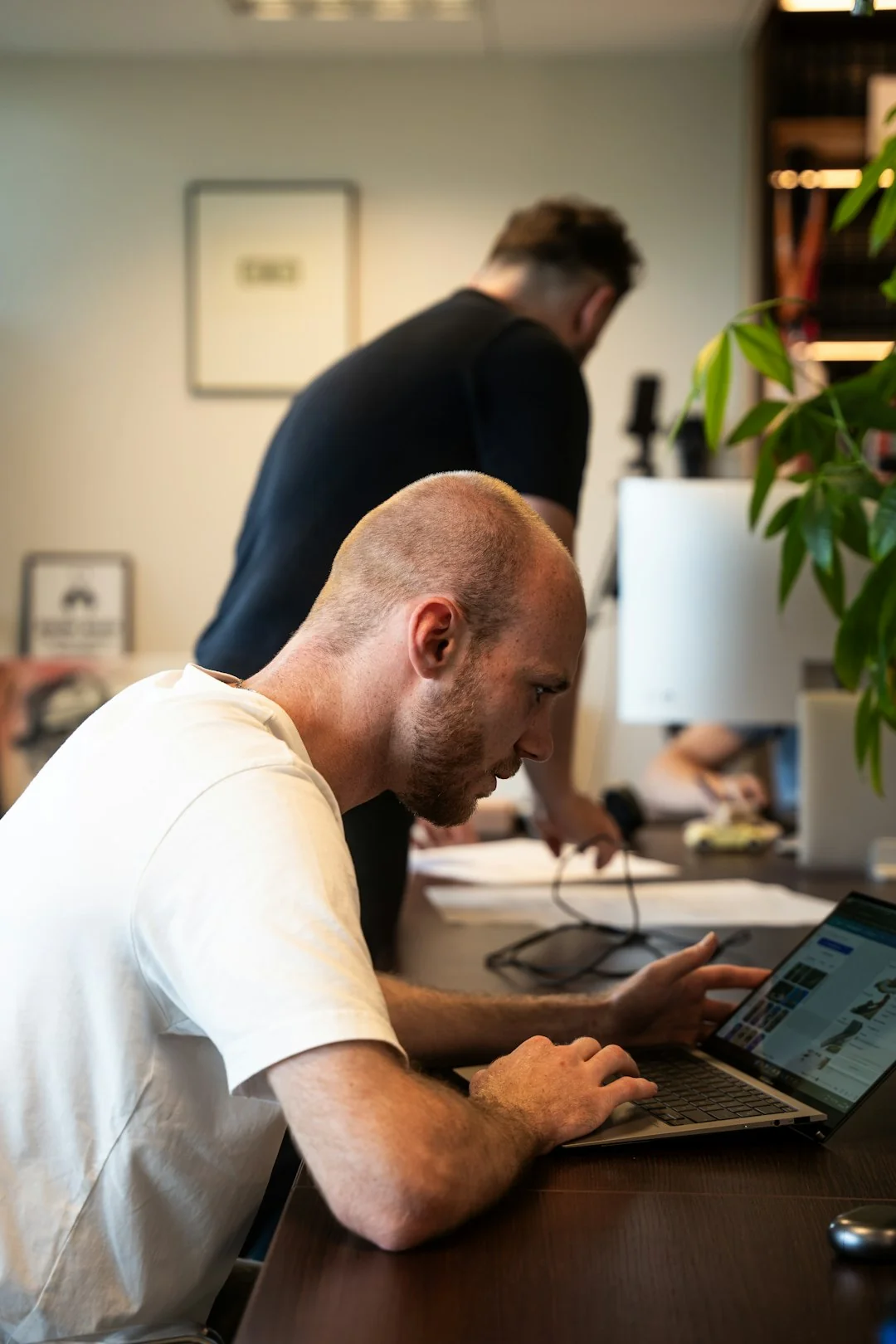 Hands typing on a laptop with cryptocurrency charts and smartphone display in view, focusing on digital finance.